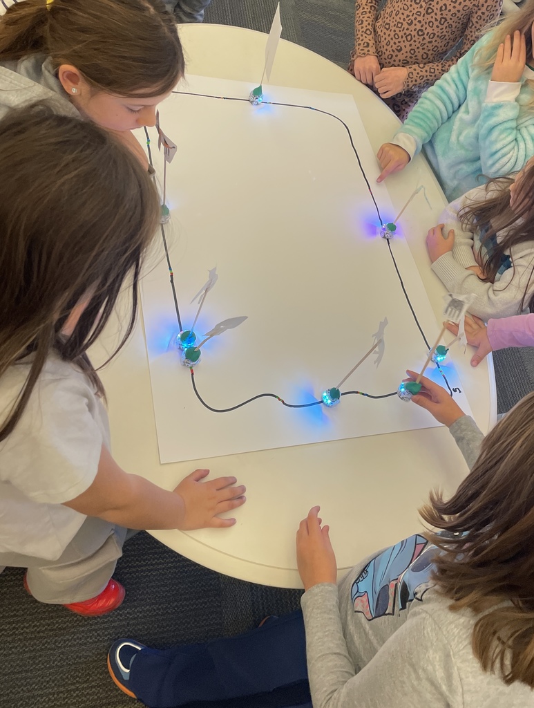 kids looking at many Ozobots going around a bit track