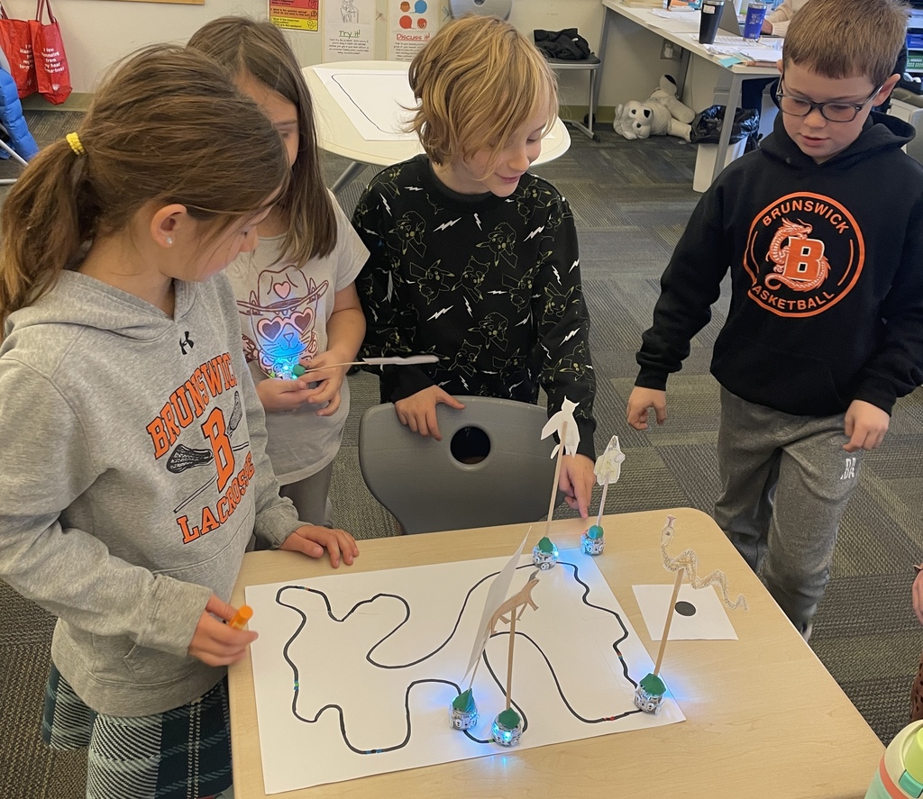 4 students watching their Ozobots going around their track