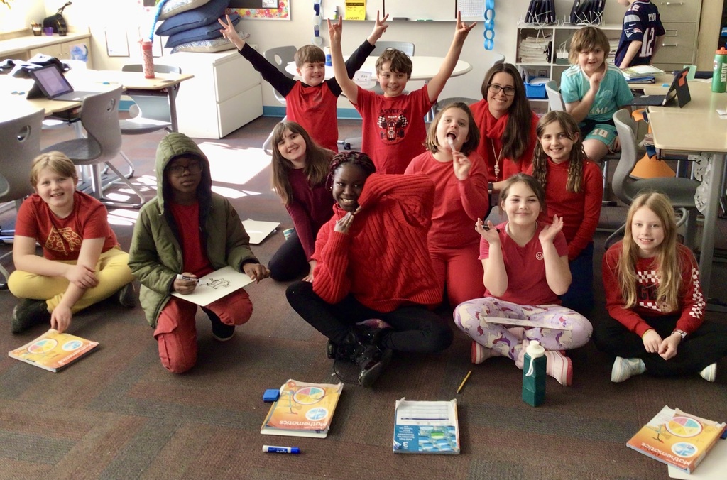 class photo with most wearing red clothing and smiling excitedly
