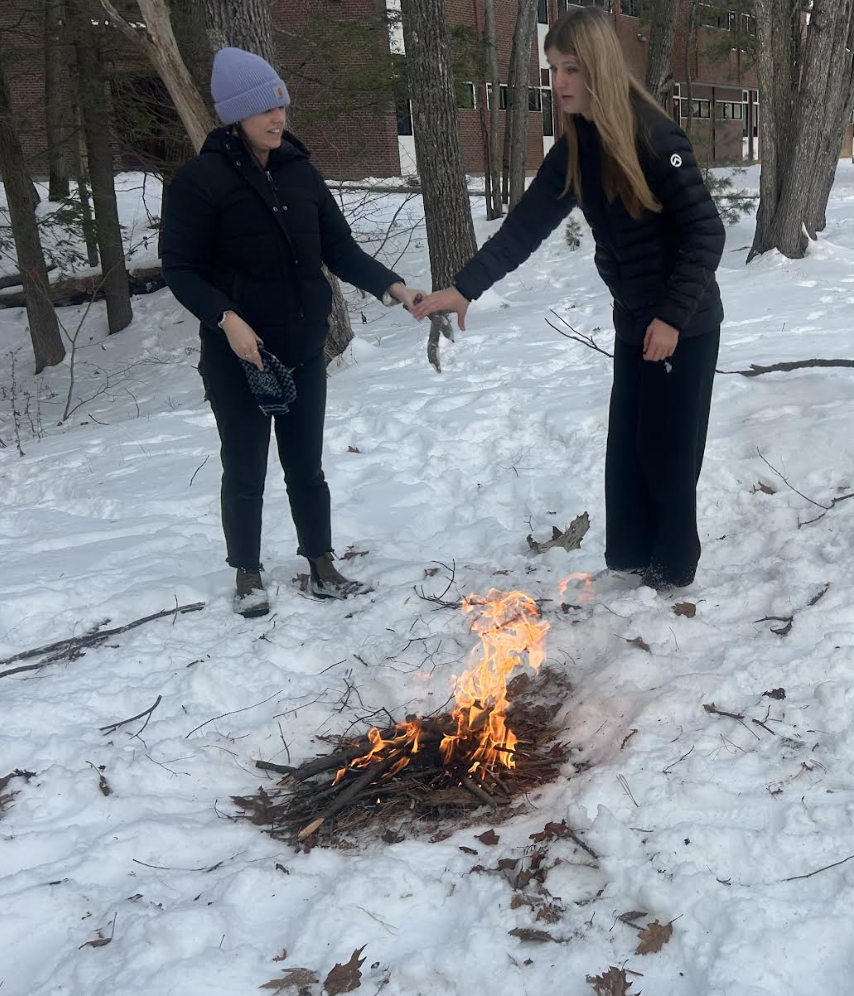 Two students building a fire outside.