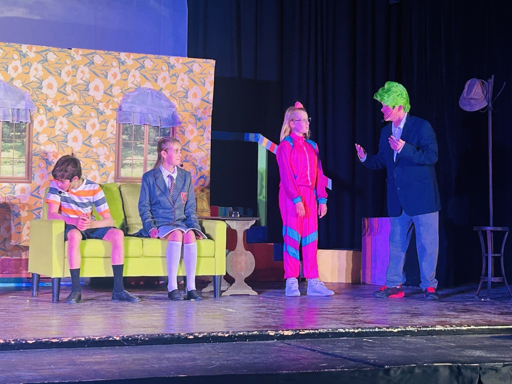 Four cast members of Matilda having a conversation and sitting on a couch.