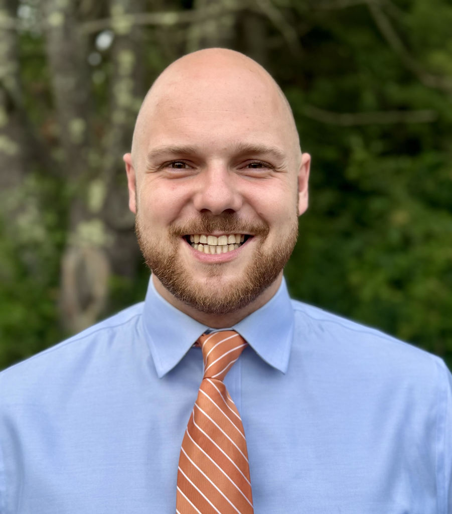 Alan Molnar in a shirt and tie with a big bright smile
