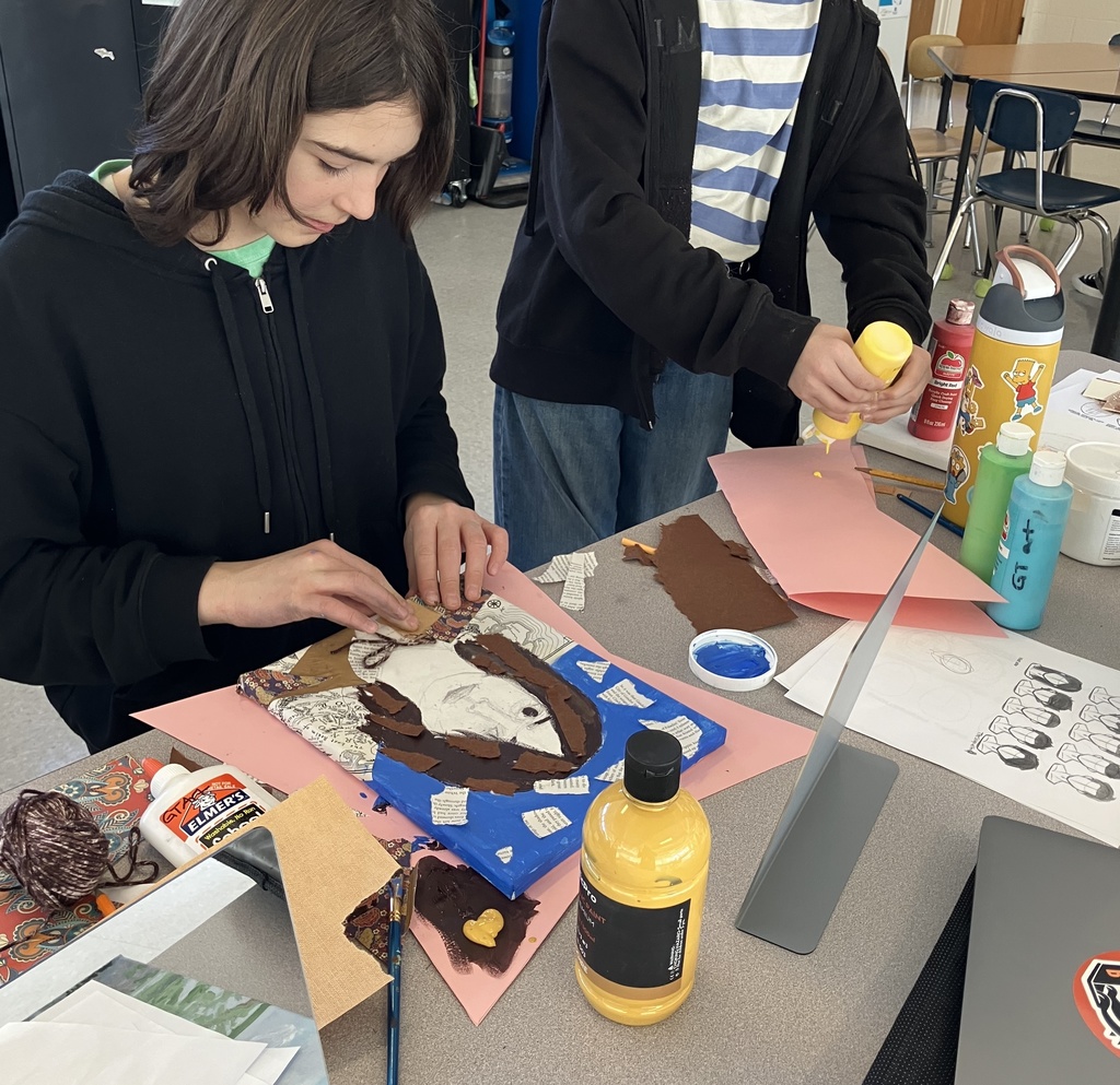 Student gluing brown paper to a self portrait.
