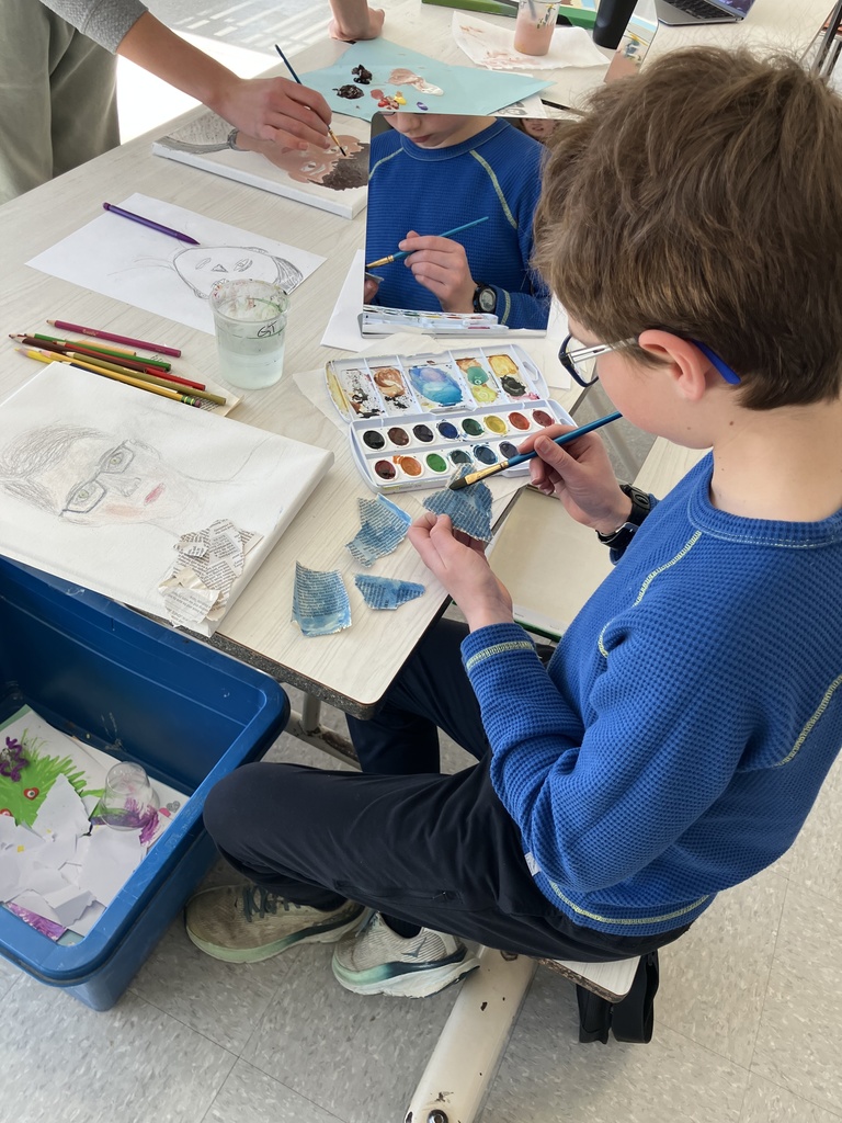 Student applying paint to newspaper at a work station.