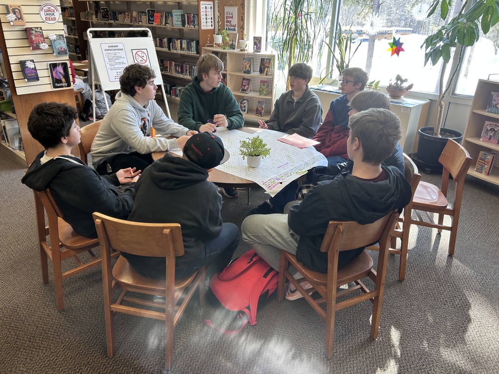 Group of BJH students sitting around a table with two BHS students having a discussion.