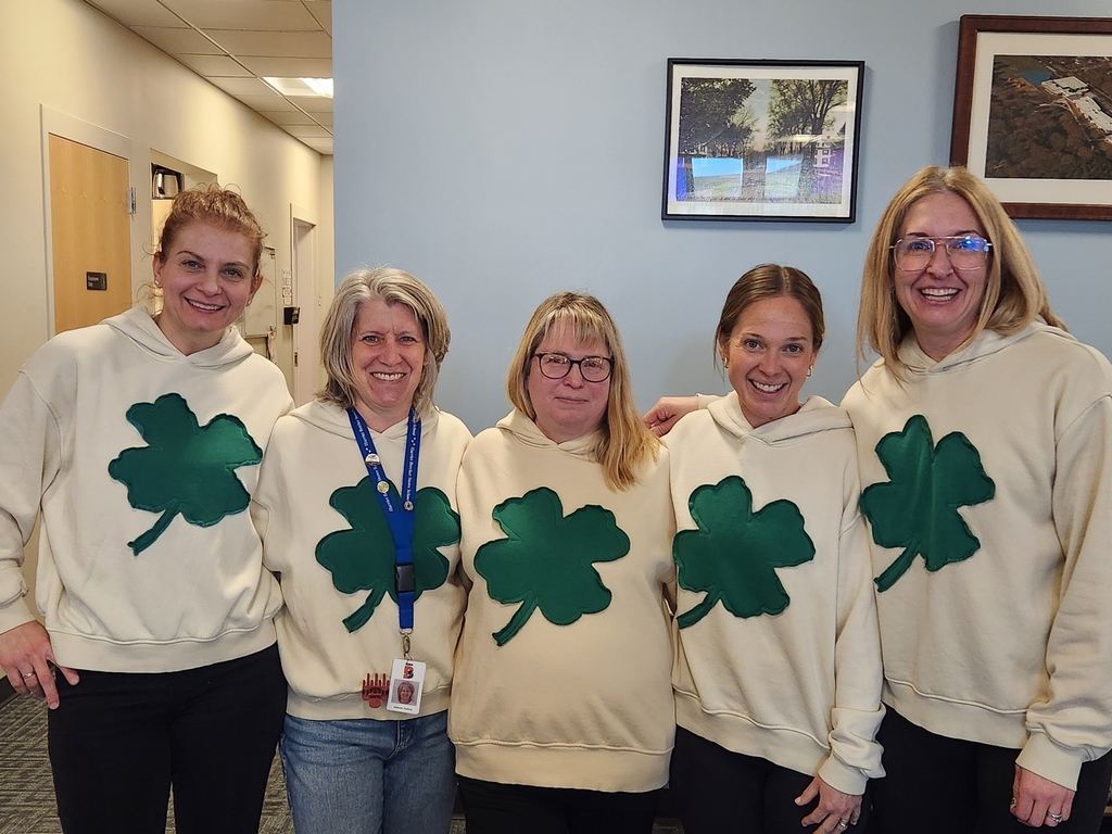 five women wearing matching clover sweatshirts