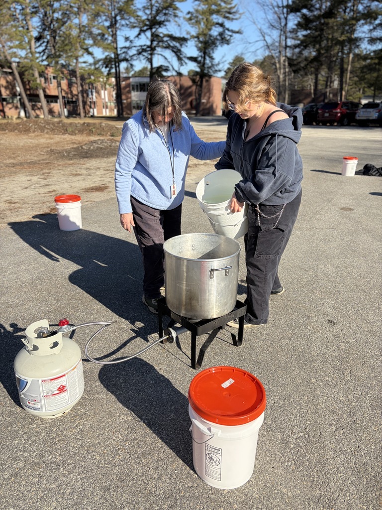 Student and teacher pouring sap into a boiling pot.
