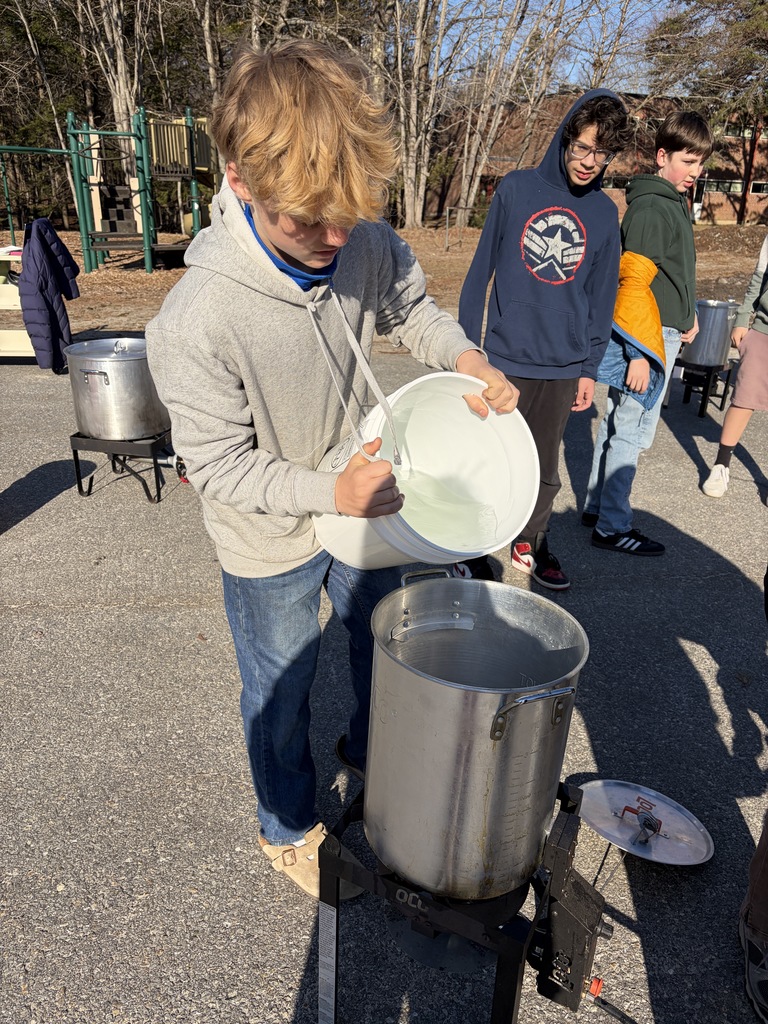 Student pouring sap into a pot to boil outside.