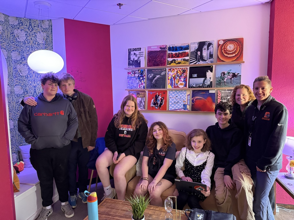 Group of  seven students and two teachers posing for a picture at a radio station.