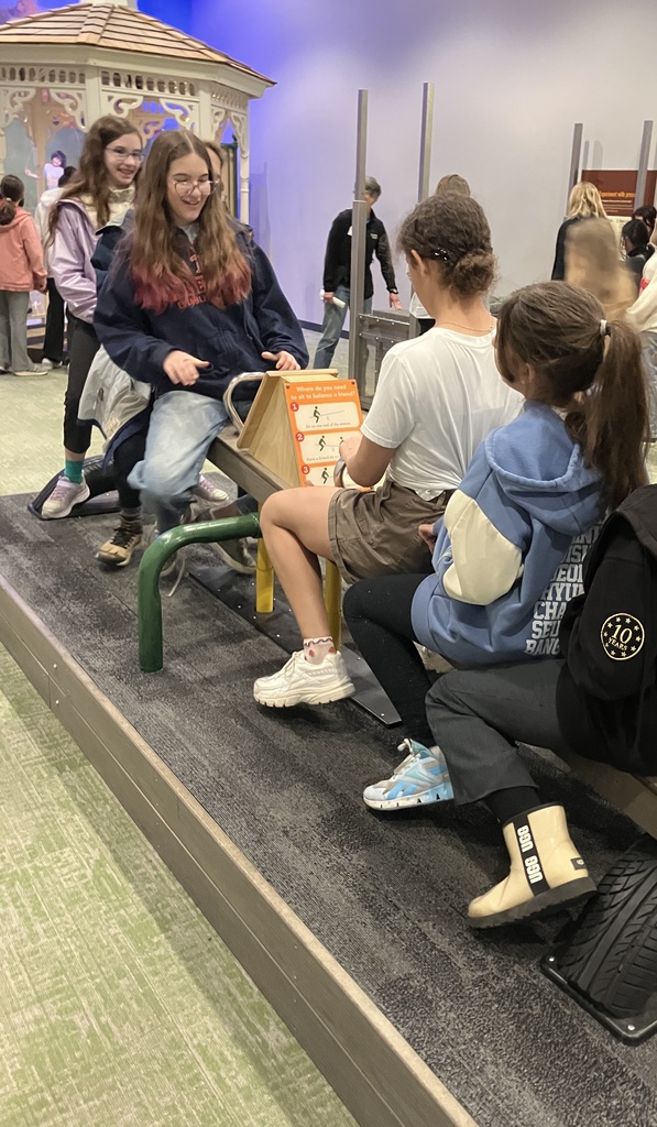 Four students use a see-saw at the Boston Museum of Science.