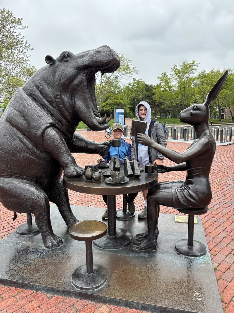 Two students pose with a statue of a Rhino and Rabbit sharing a meal in Boston.
