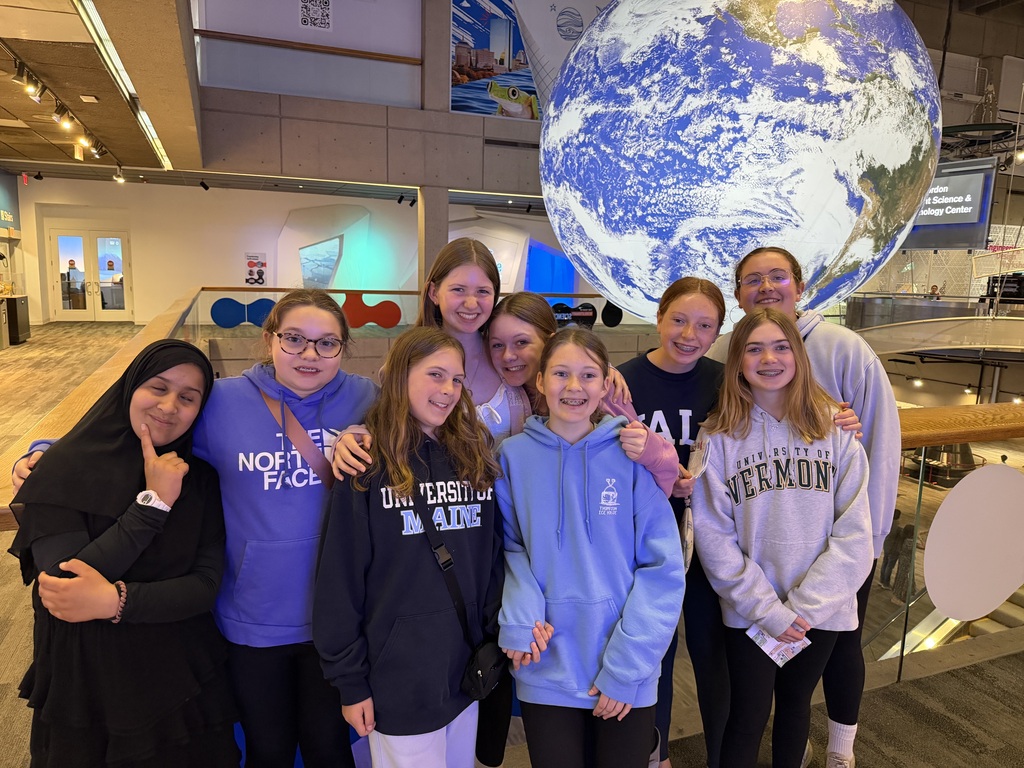 Ten students pose in front of a globe of the Earth at the BOston Museum of Science.
