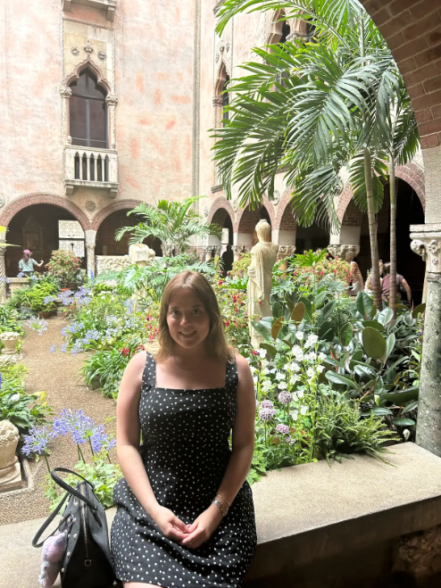 woman sitting in front of a flower garden with statues