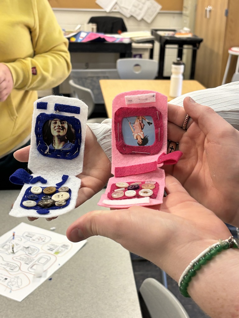 Student holding two felt phones they made.