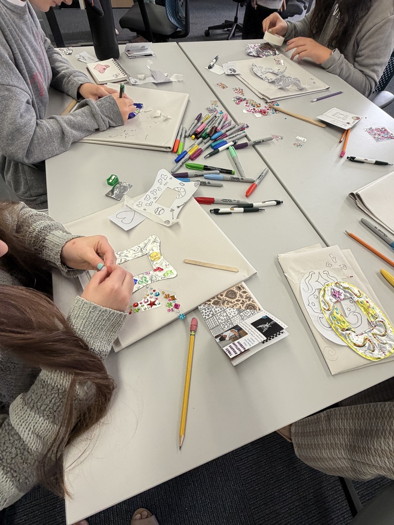 Students at a table making tin frames with gems.