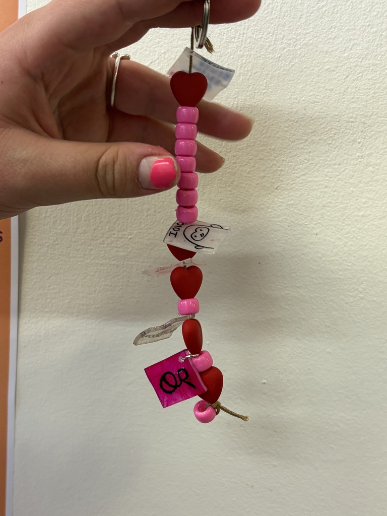 Student holding pink chain with charms.
