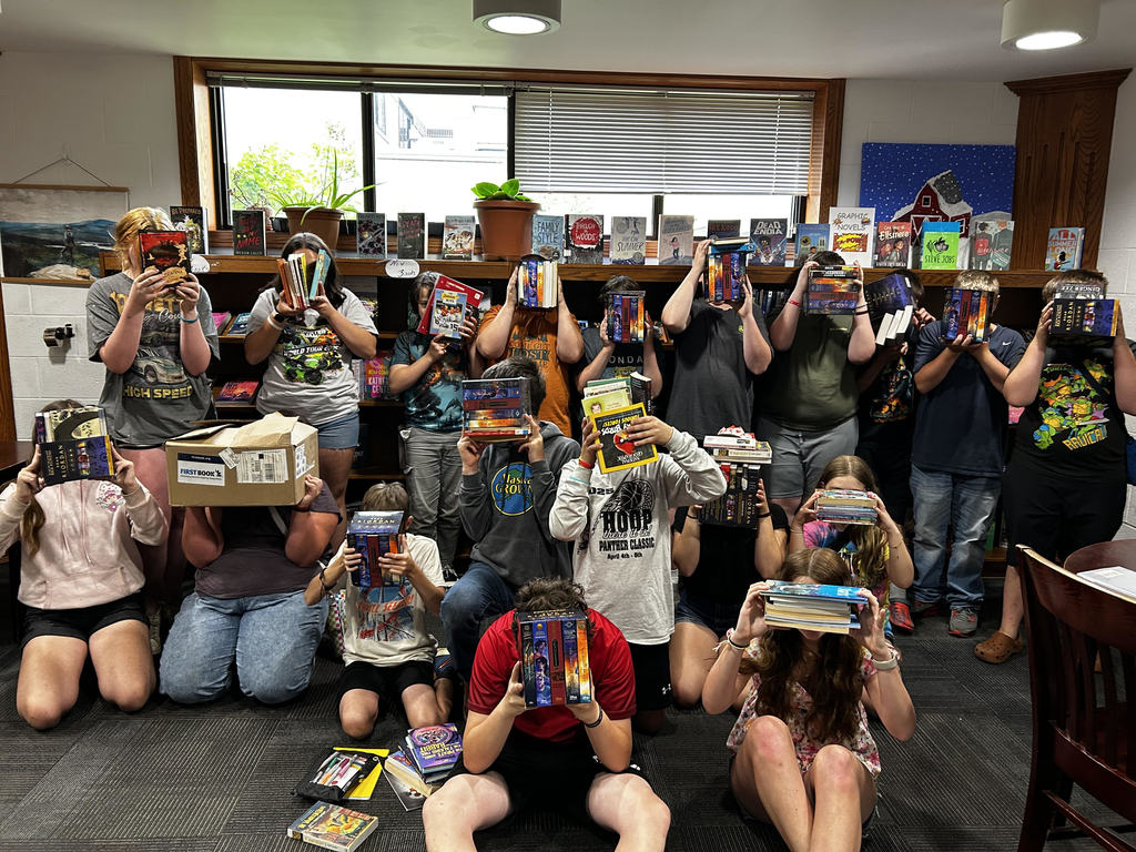 Class with books covering their faces