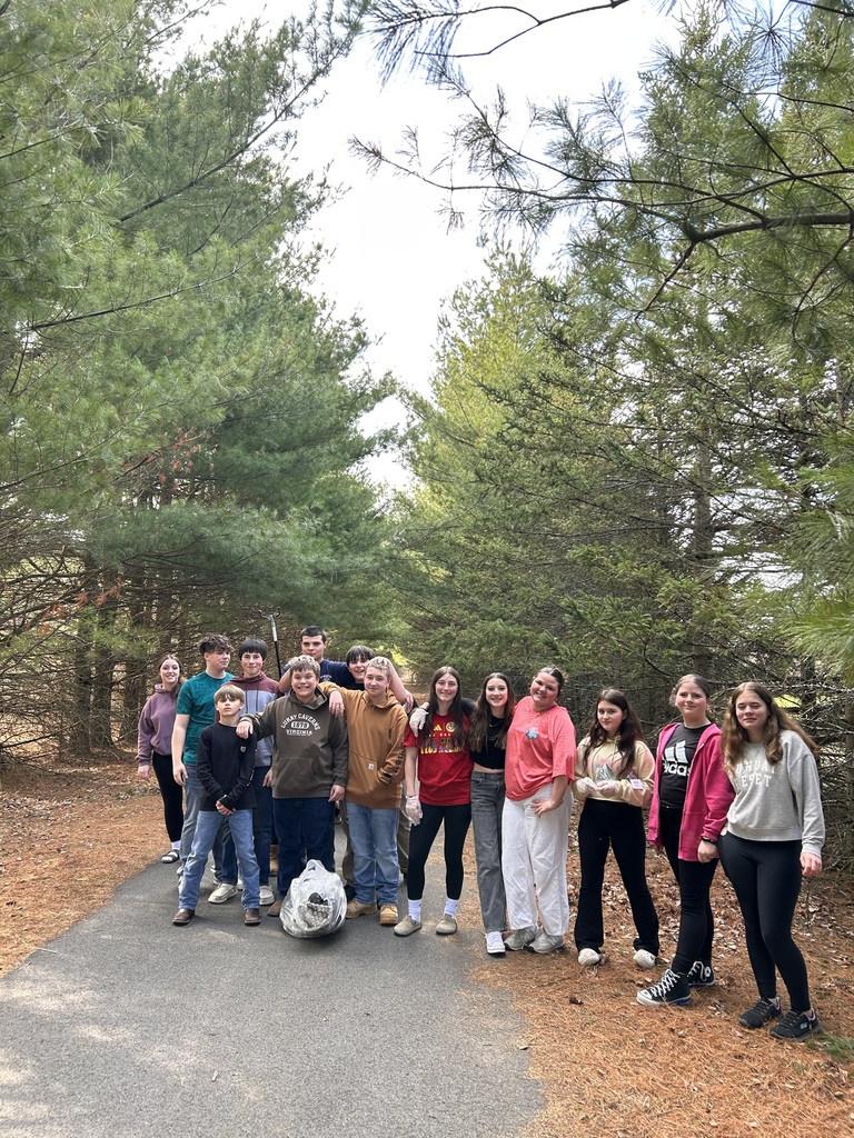 A group of students with evergreens and paved trail
