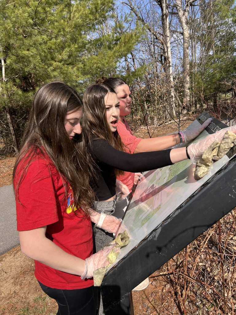 Three students washing a sign