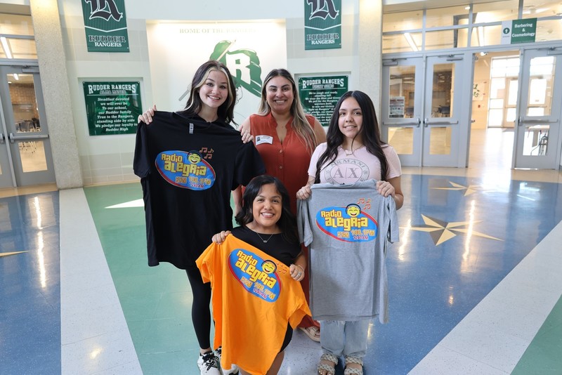 Radio Alegria Reporter takes a photo with Rudder Students holding radio station t-shirts.
