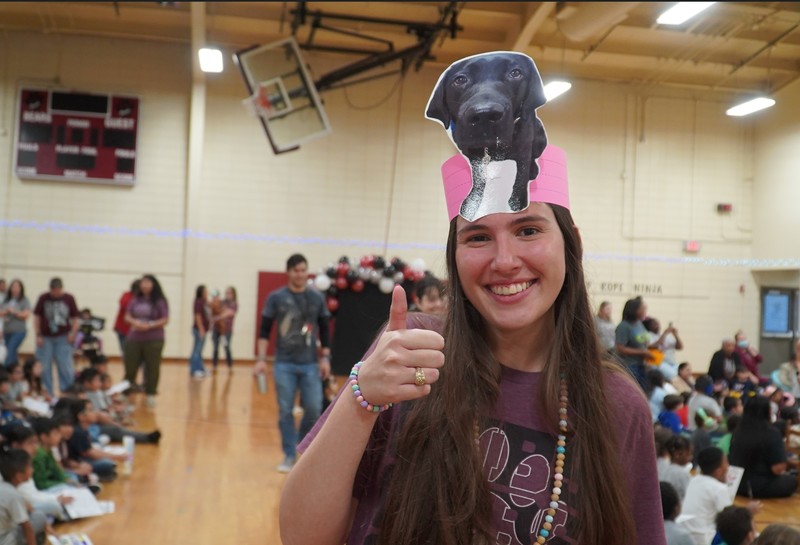 A Teacher poses wearing a hat that has June's image on it.