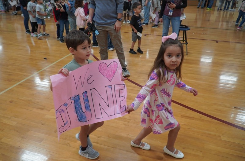 Students hold a sign saying, We love June.