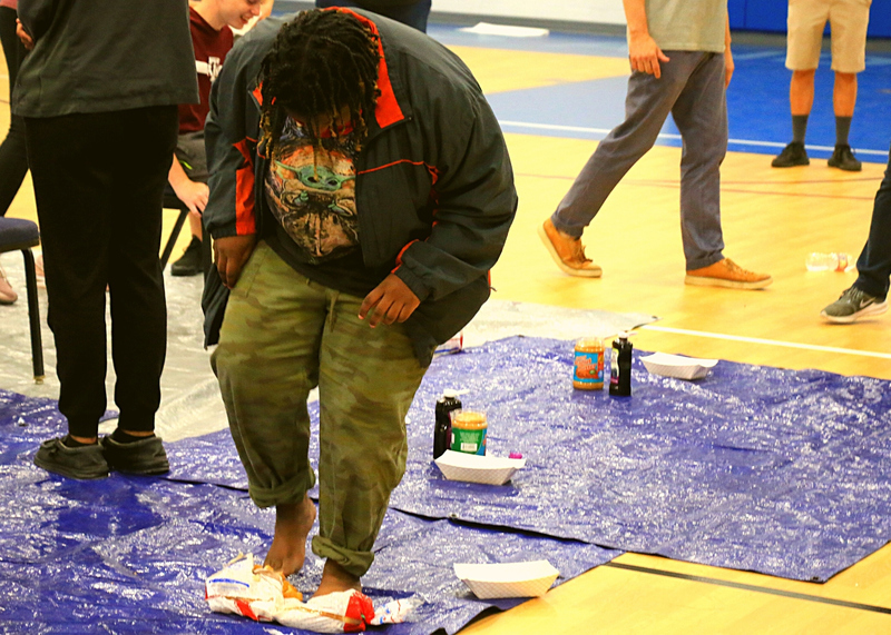 student standing in peanut butter on blue tarp