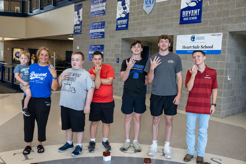 A group of people wearing various shirts and shorts standing in a circle, possibly at a school.