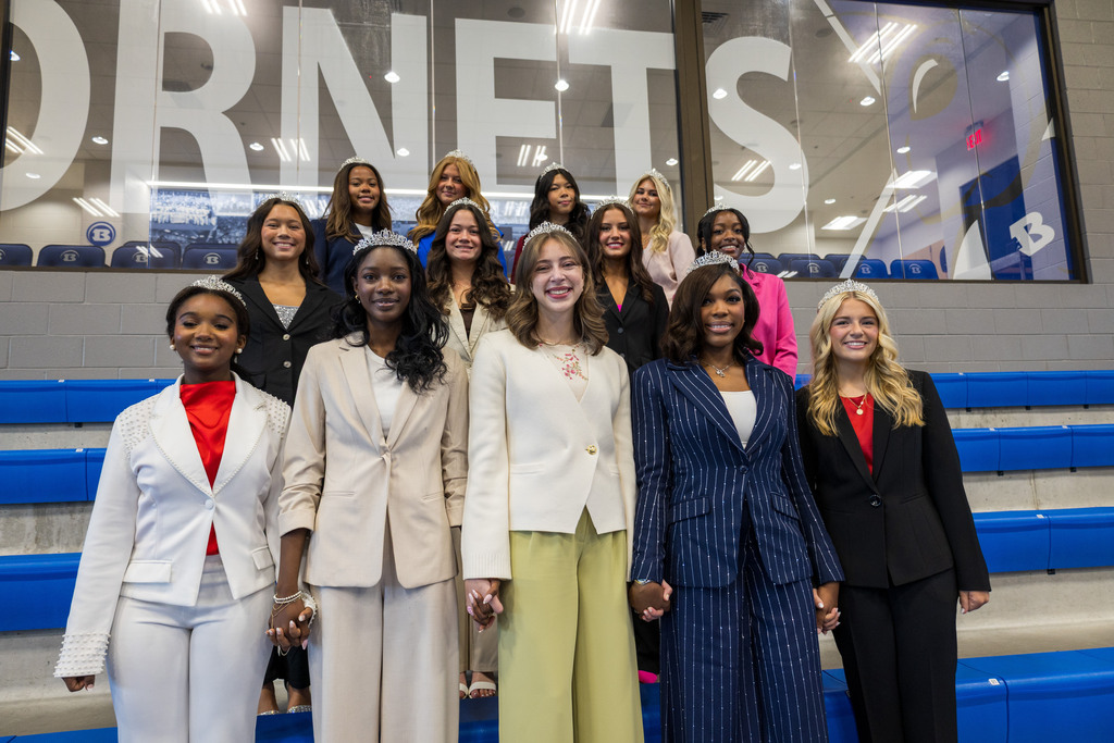 A group of women in professional attire standing on bleachers, smiling, and posing for a photograph.