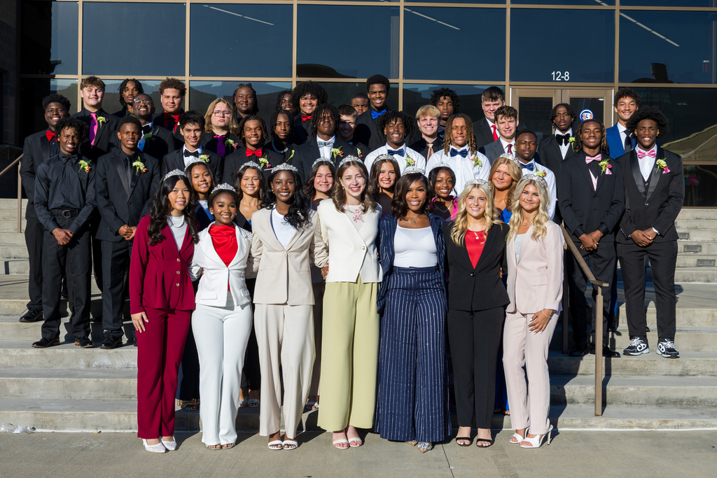 Students, staff, and administrators pose for a photo in front of the school's main entrance.