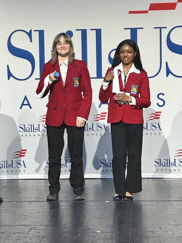 two students with their medals on stage 