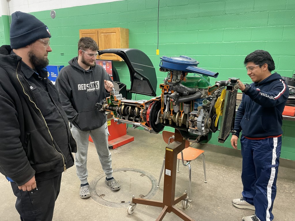 Students are looking at internals of an engine . 