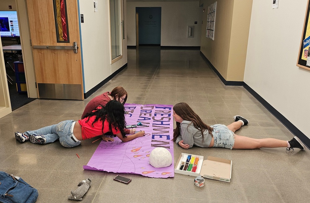 Freshman students working on their homecoming parade float banner