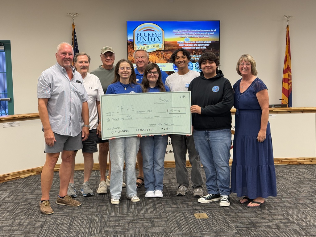 A group of people posing with a large check. A woman holds the check with both hands.