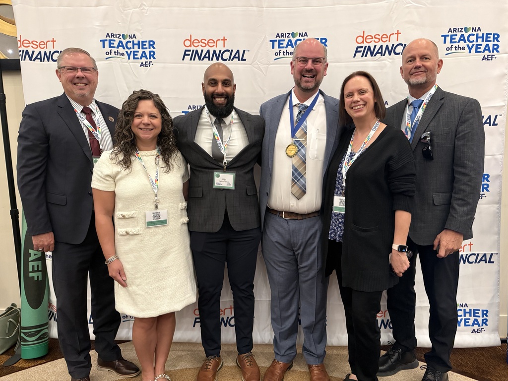 Six people in formal attire stand together in front of a banner that reads "Desert Financial" and "Teacher of the Year."