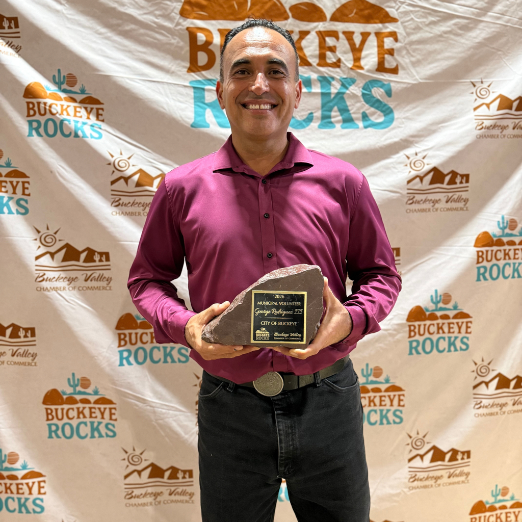 man smiling and holding an award