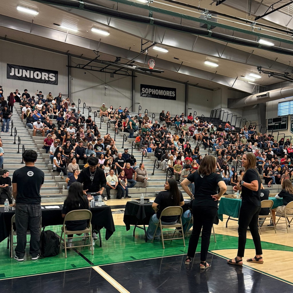 People sitting in the stands in a school gym.
