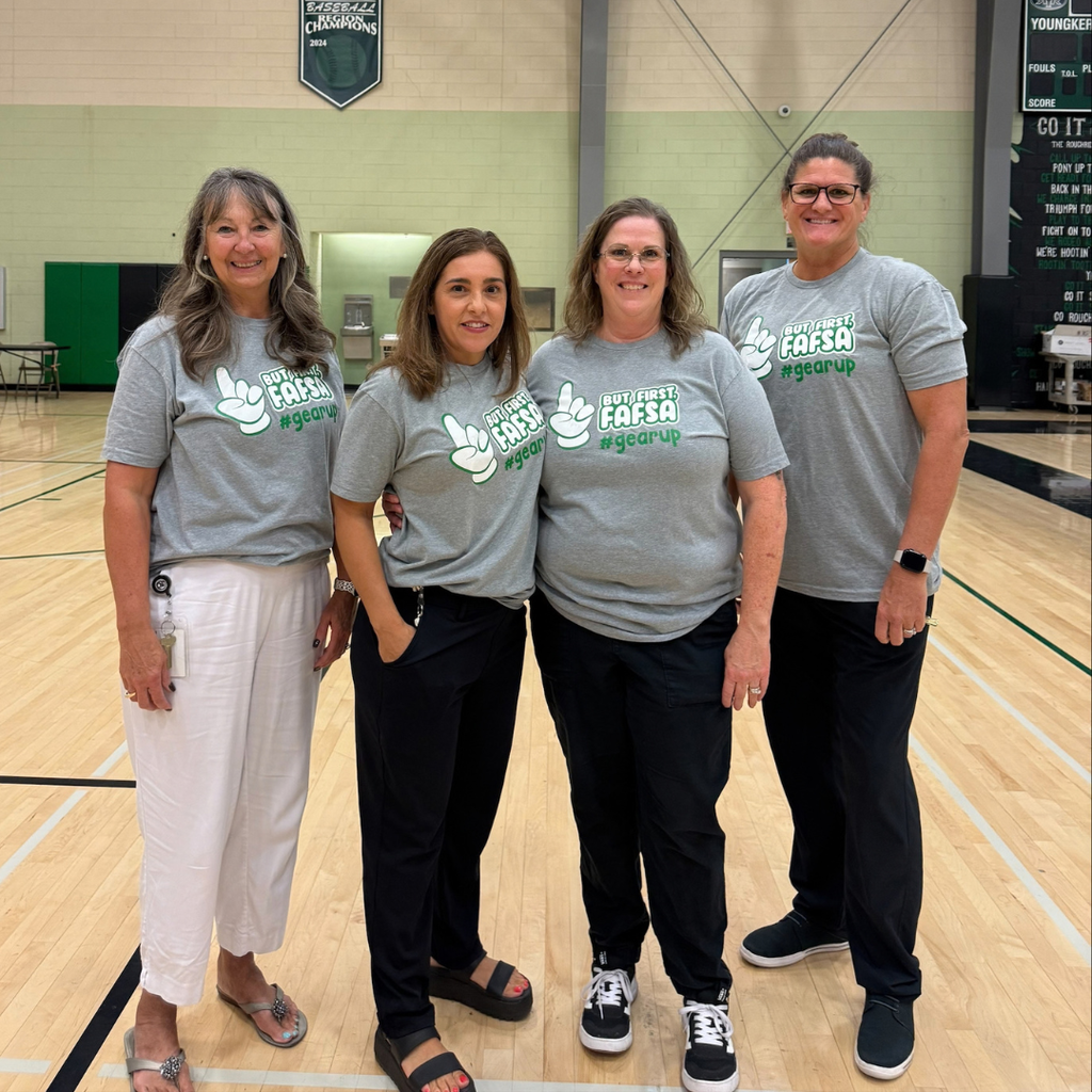 Four adults wearing gray T-shirts while posing for a picture.