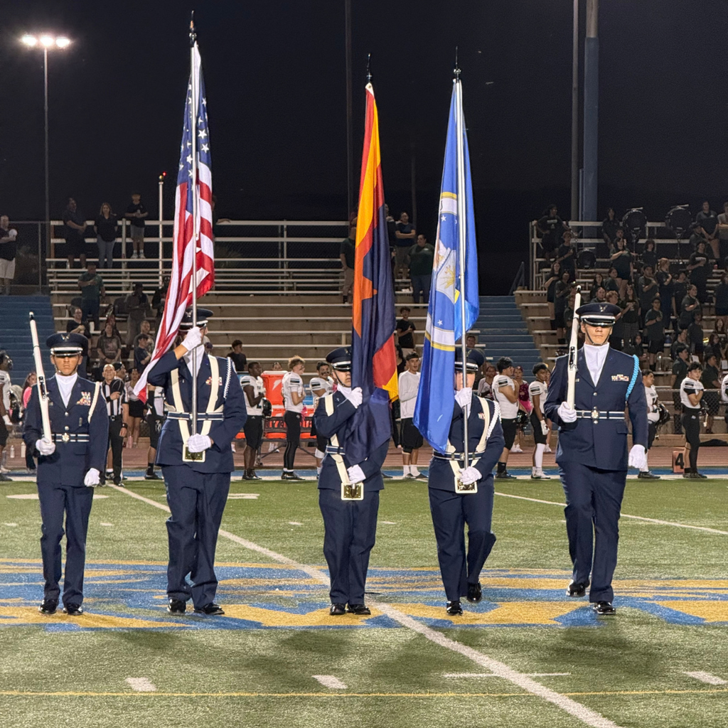 Five JROTC personnel carrying flags on a football field.