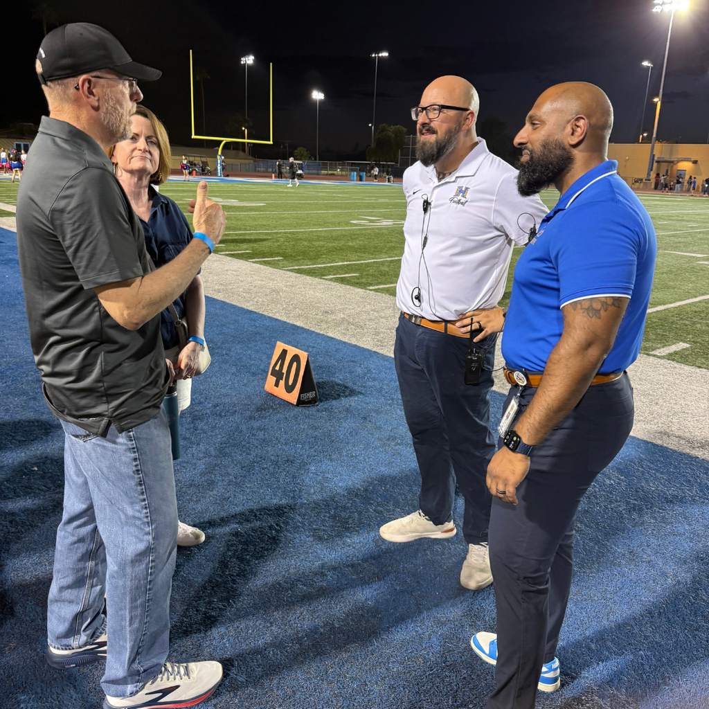 Four people conversing on a football field.
