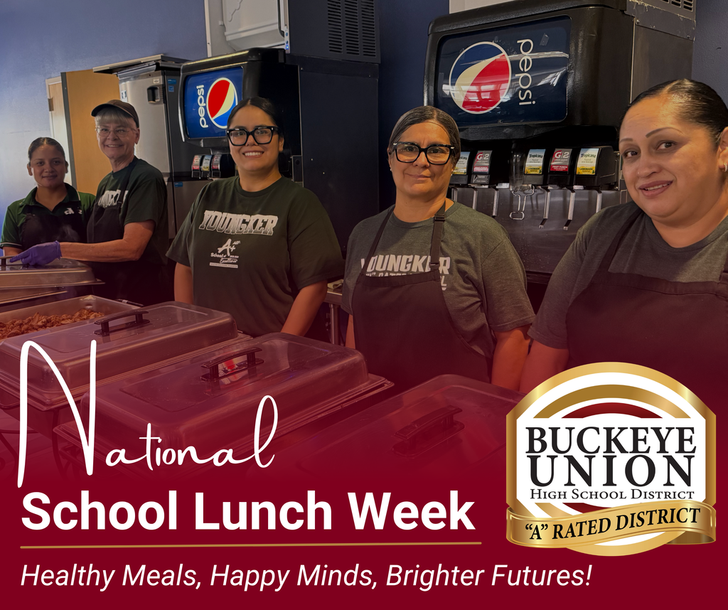 Four food service workers stand behind a table, smiling.
