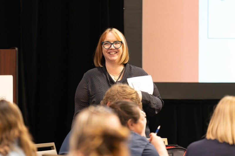 person smiling while presenting to a group of people
