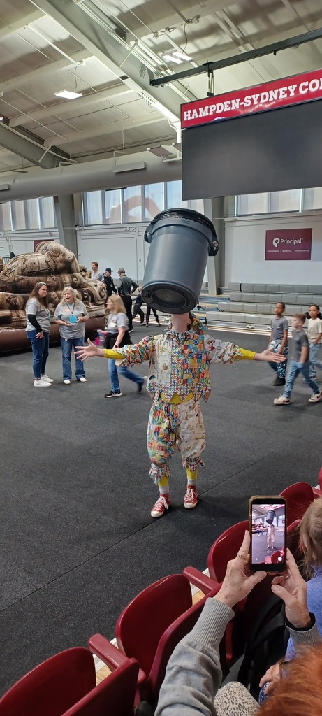Jester balancing a large trash can on their chin