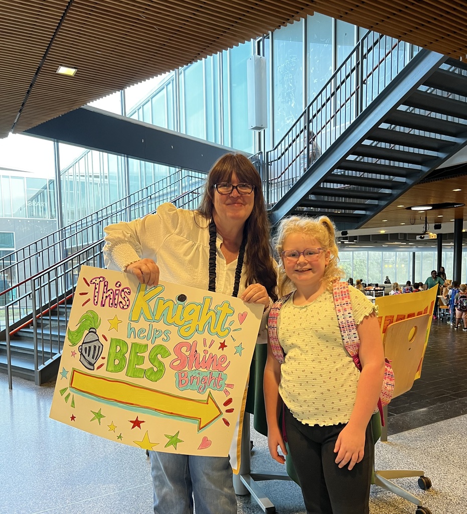 Student poses with staff member and poster that "Student helps BES shine bright"