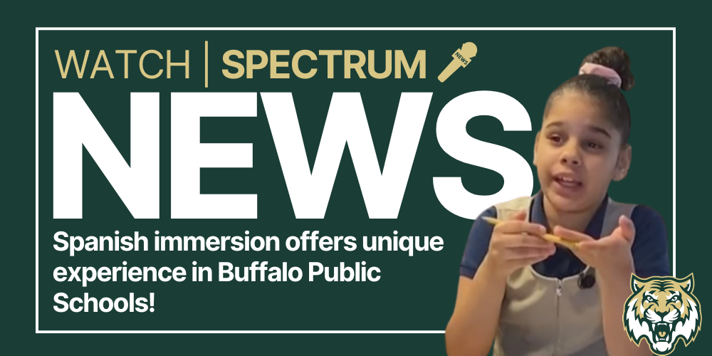 Promotional graphic reading “Watch Spectrum News.” Large text says “NEWS,” with a headline below stating “Spanish immersion offers unique experience in Buffalo Public Schools!” The design includes an image of a student speaking while holding an object, set against a dark green background with a microphone icon and a buffalo mascot logo in the corner.