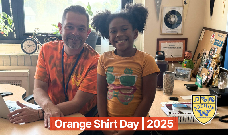 A teacher and student sitting at desk wearing orange shirts