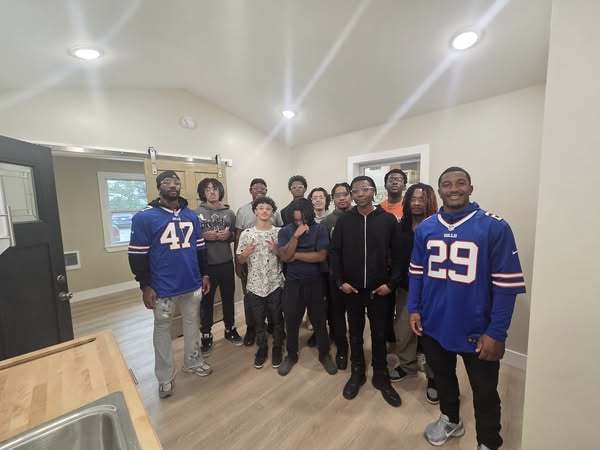 Buffalo Bills in front of a student built house with students getting photos taken