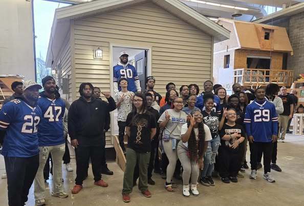 Buffalo Bills in front of a student built house with students getting photos taken