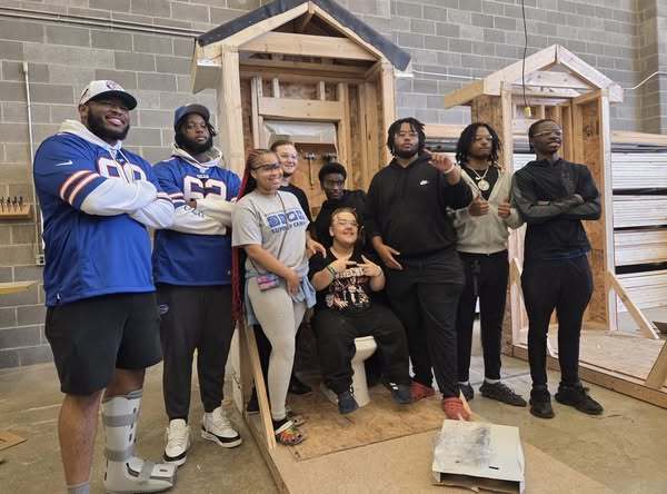 Buffalo Bills in front of a student built house with students getting photos taken