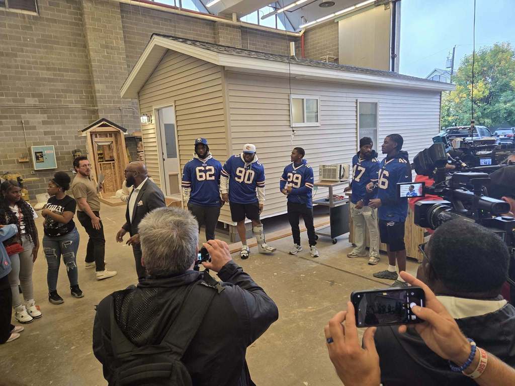 Buffalo Bills in front of a student built house with students getting photos taken